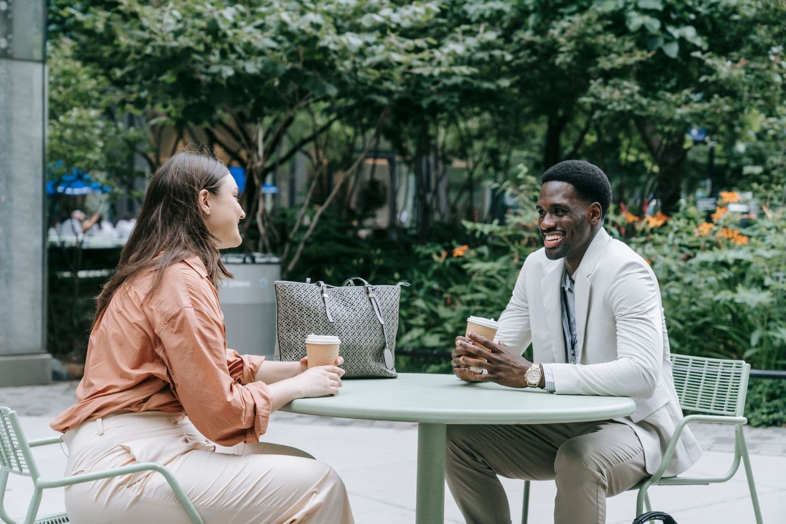 Two people talking over coffee at an outdoor café table