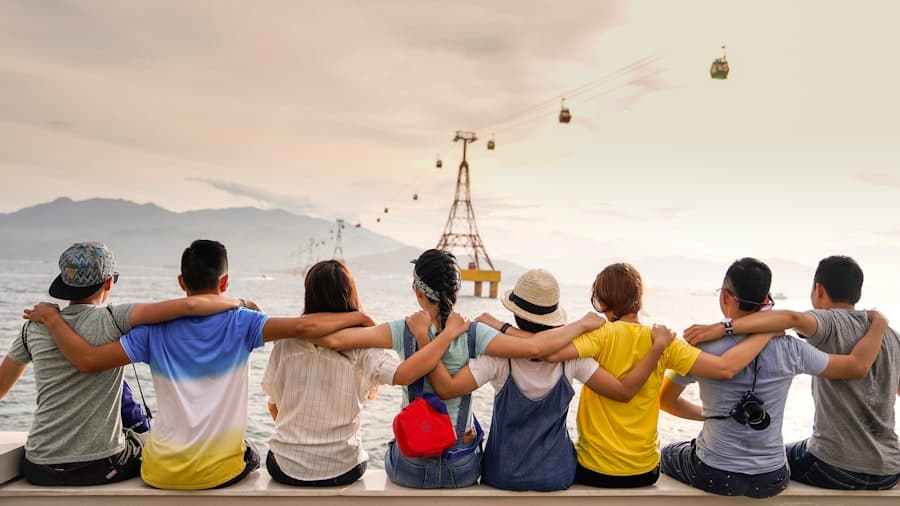 A group of friends with arms around each other looking out at a scenic view